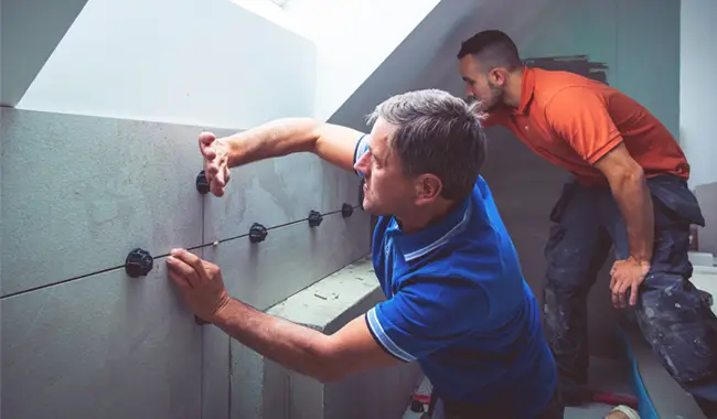 Fliesenleger montieren große, moderne Fliesen an einer Badezimmer Wand